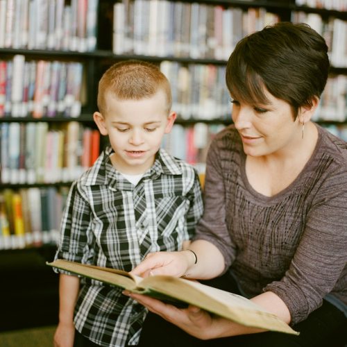 boy in gray sweater beside boy in gray and white plaid dress shirt